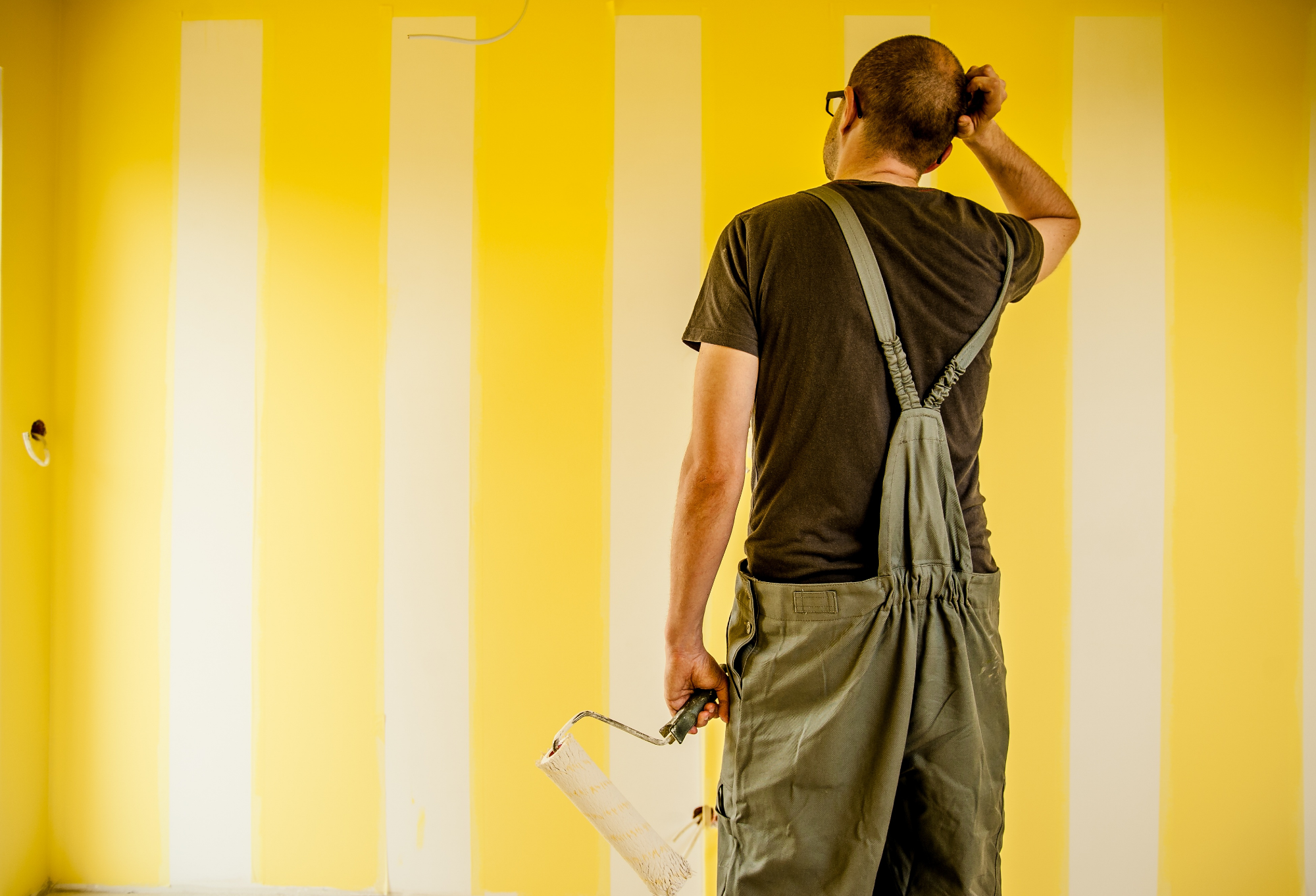 peintre devant un mur jaune